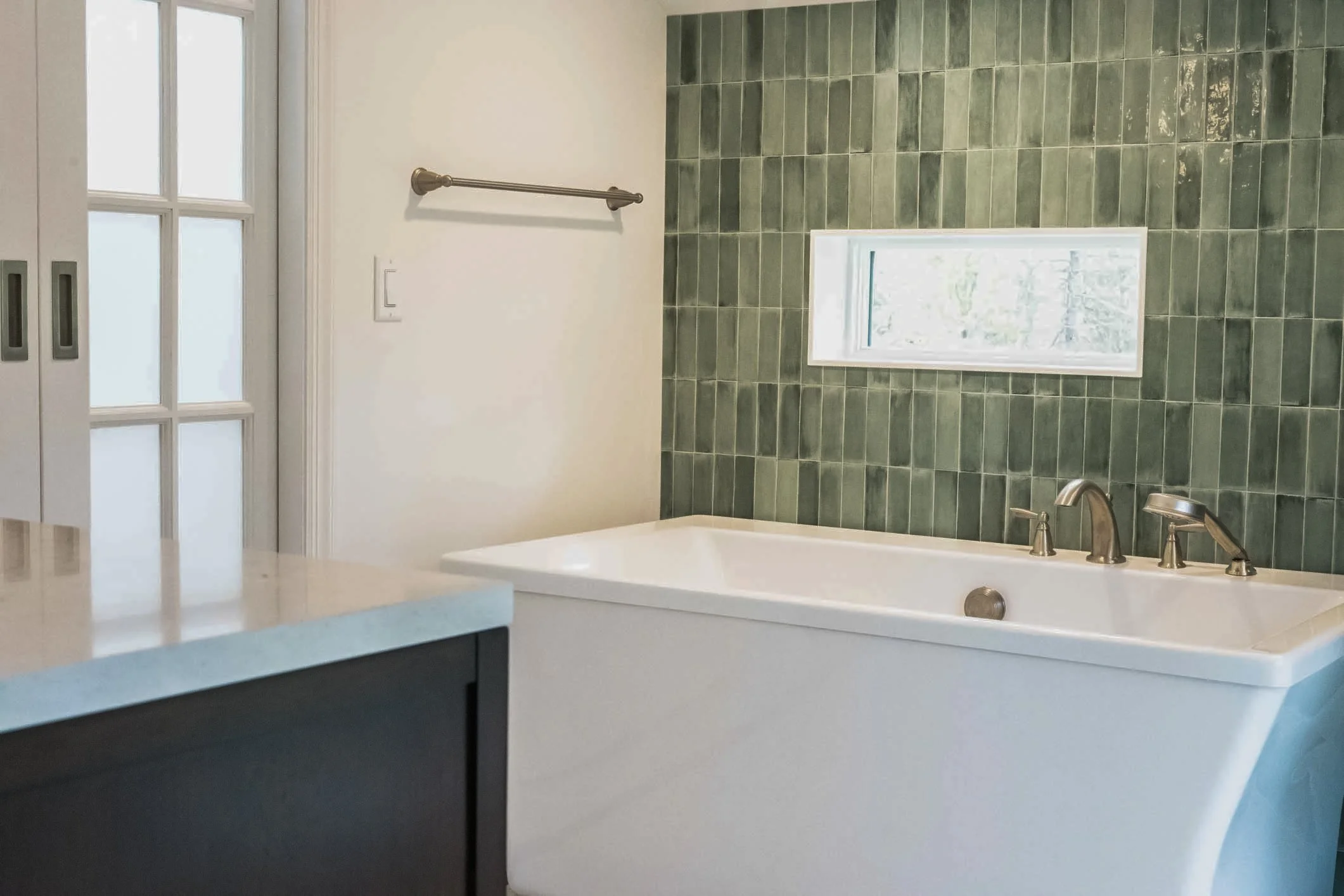 custom green tile surrounding soaking tub with inset window