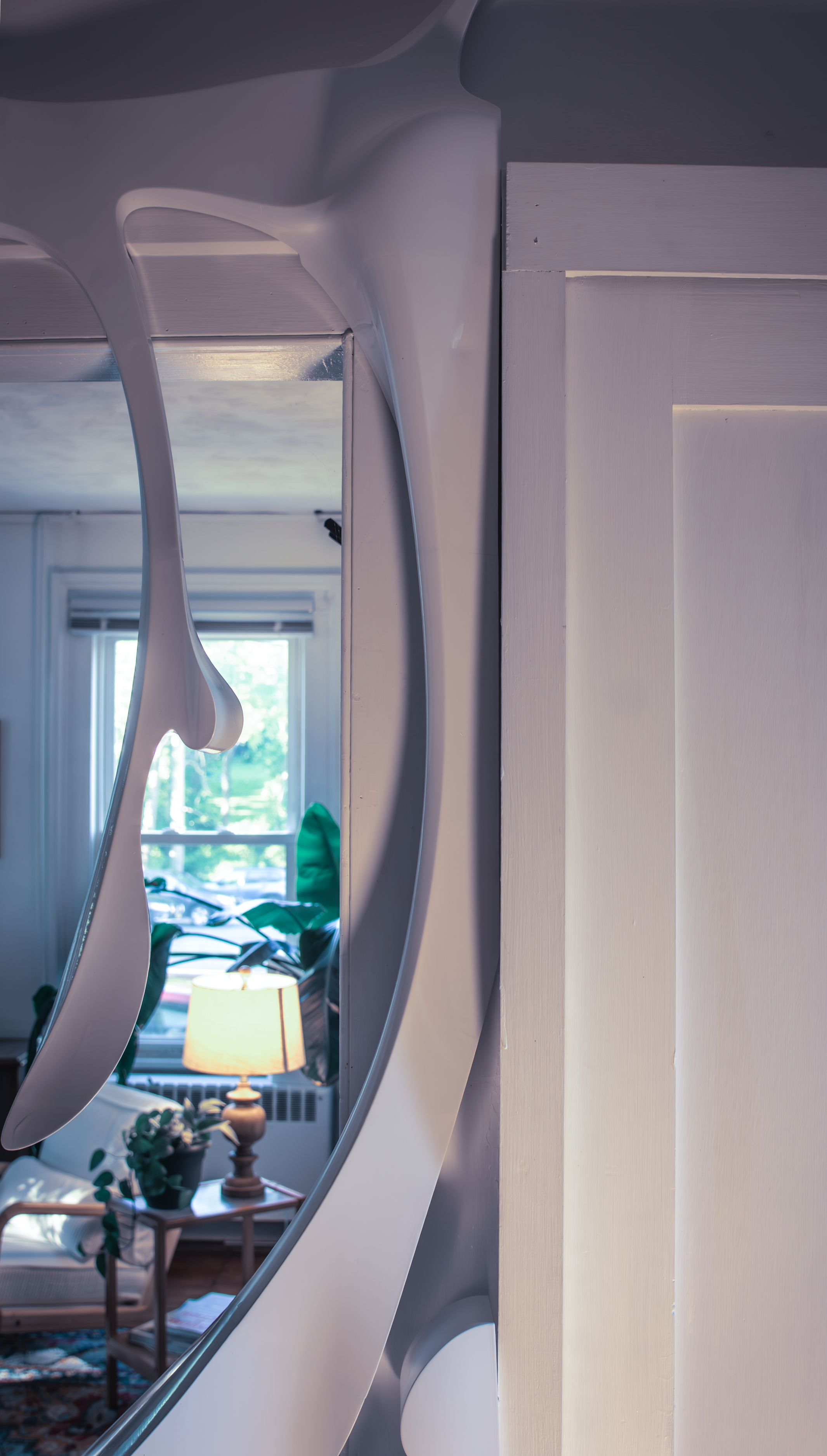 Detail view of the white sculpture with a mid century modern lamp in the background