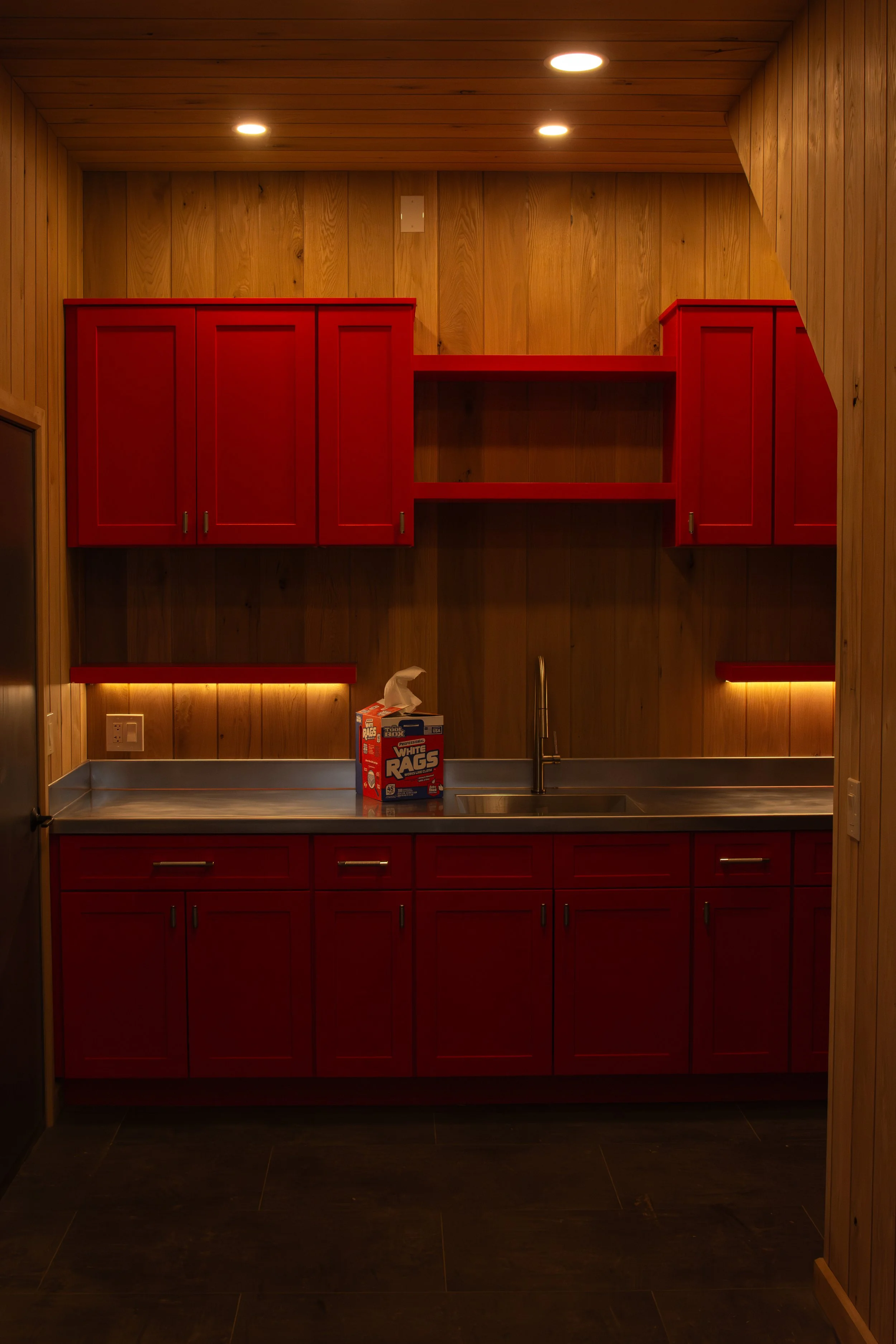 custom red cabinets with custom stainless steel countertop and undercabinet lighting