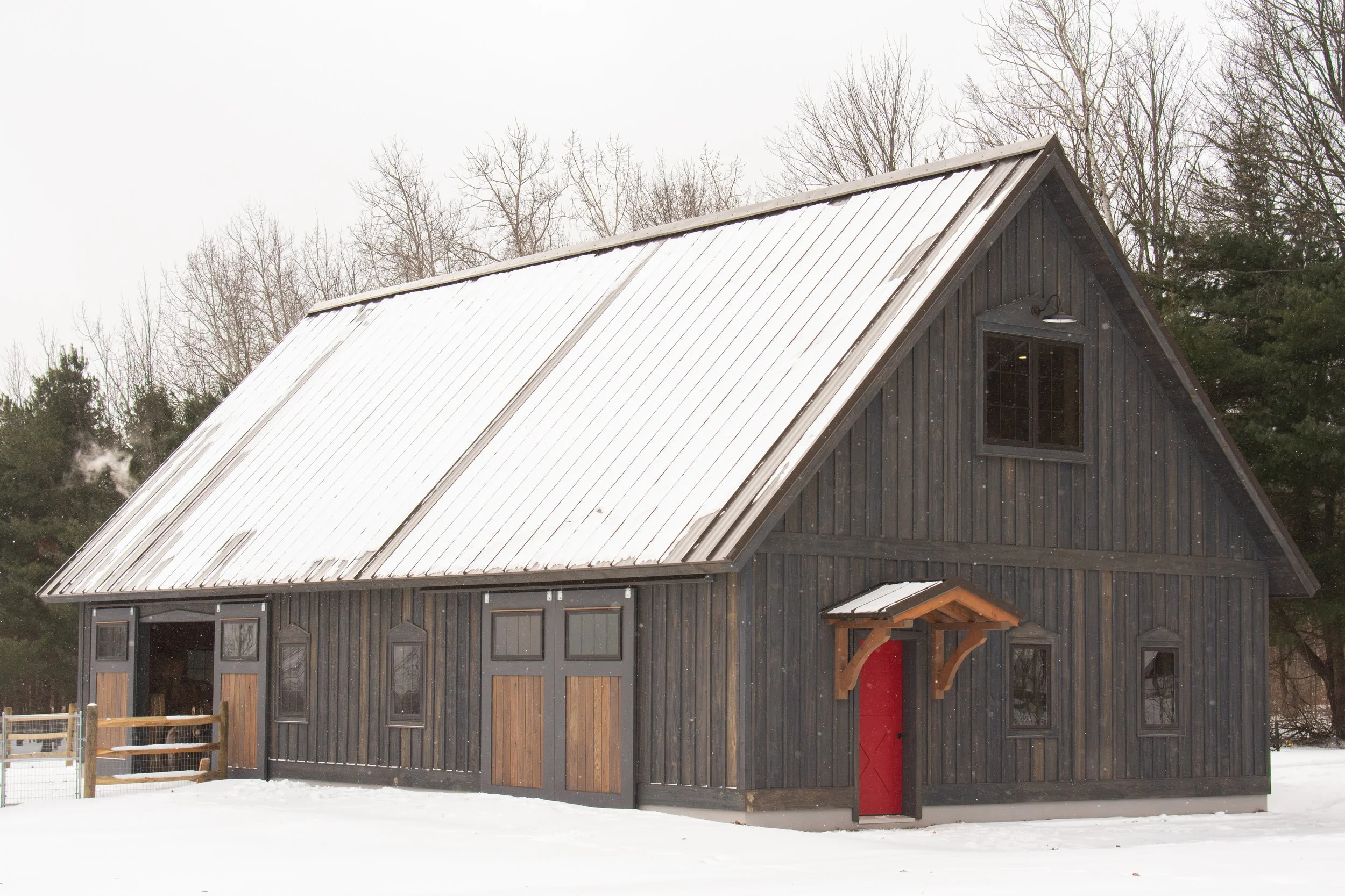 a custom barn with rustic hemlock and a red accent entry door