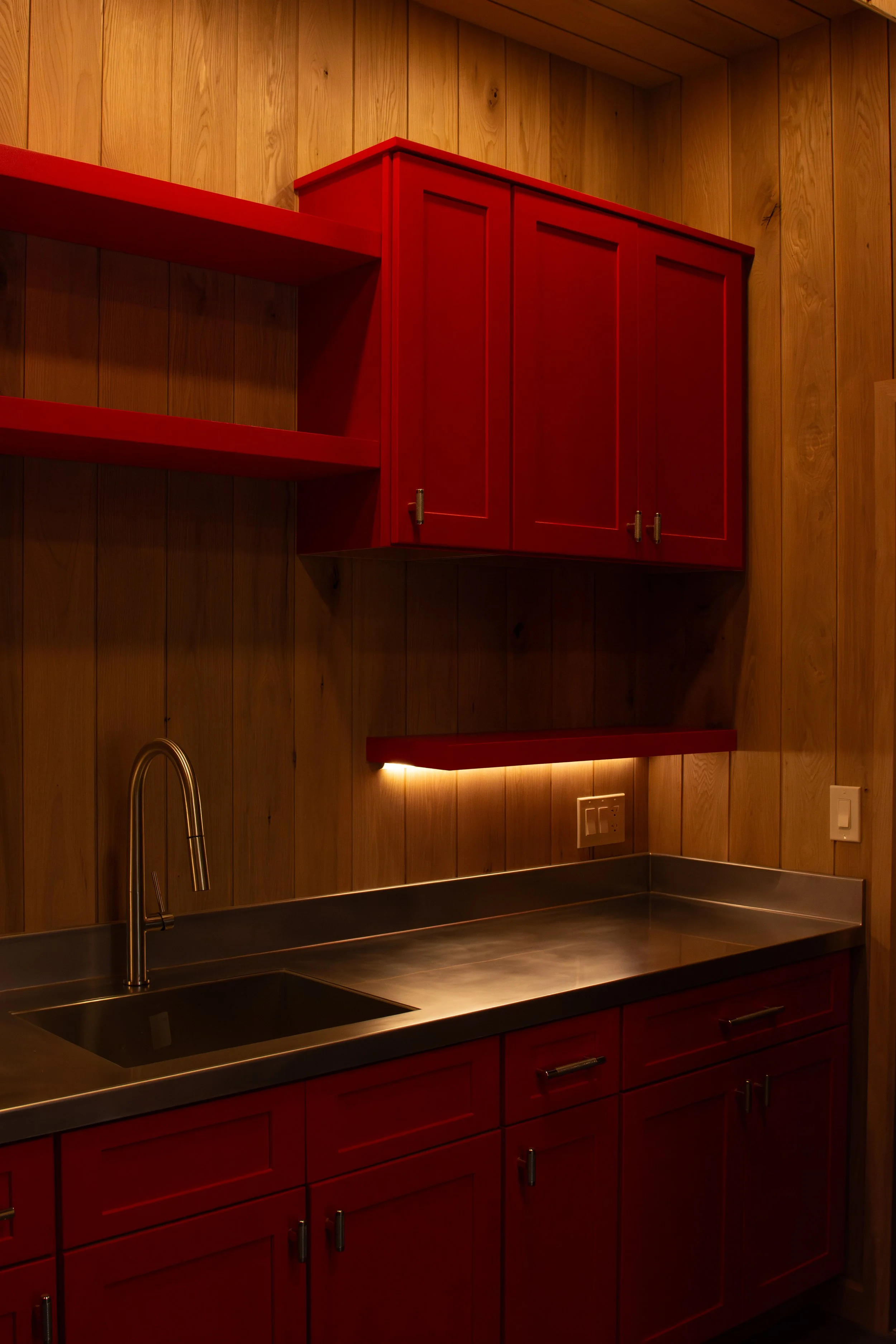custom red cabinets with custom stainless steel countertop and undercabinet lighting
