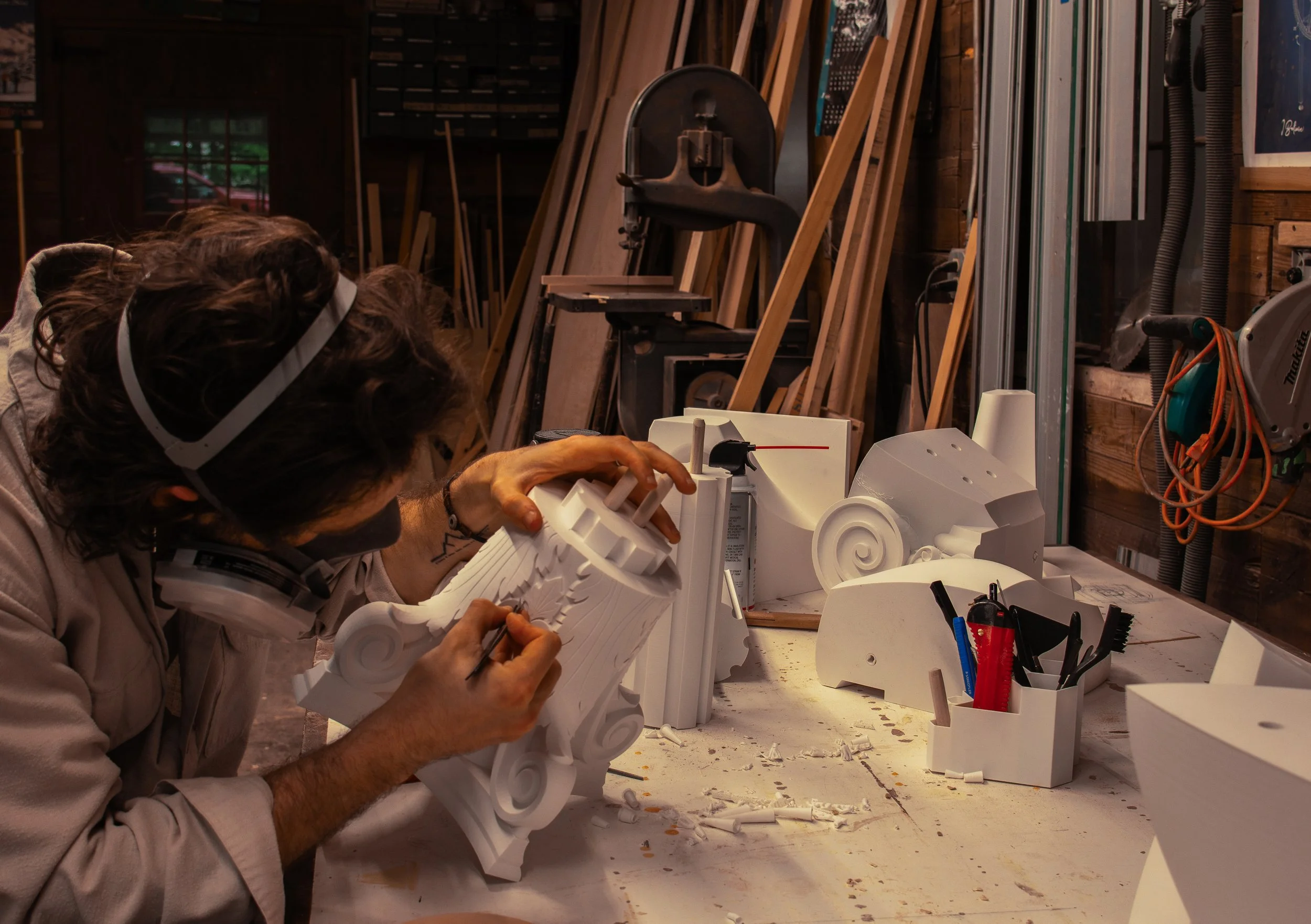 A man works on sculpting the pieces of the project in a woodshop