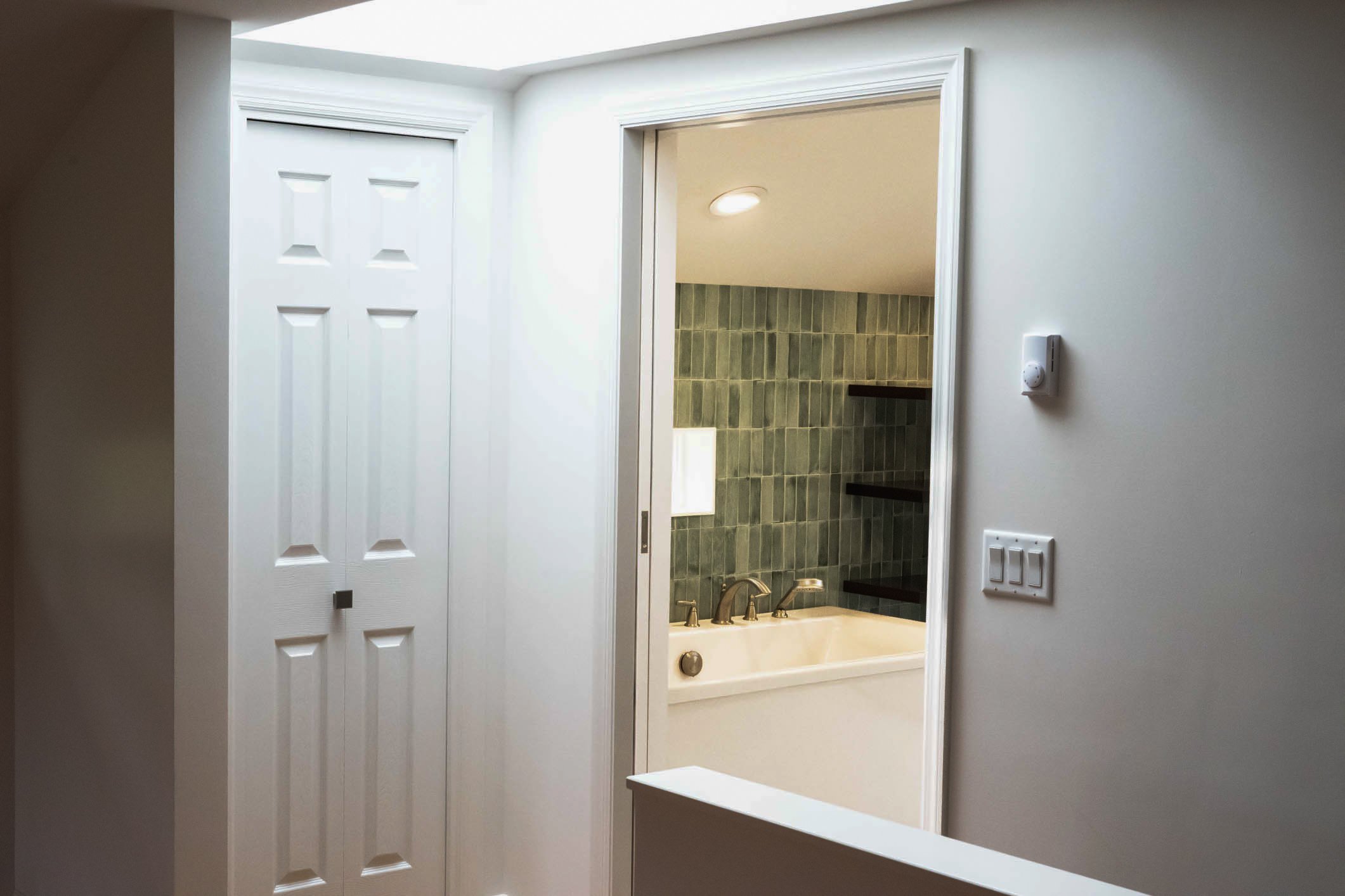 custom green tile surrounding soaking tub with inset window
