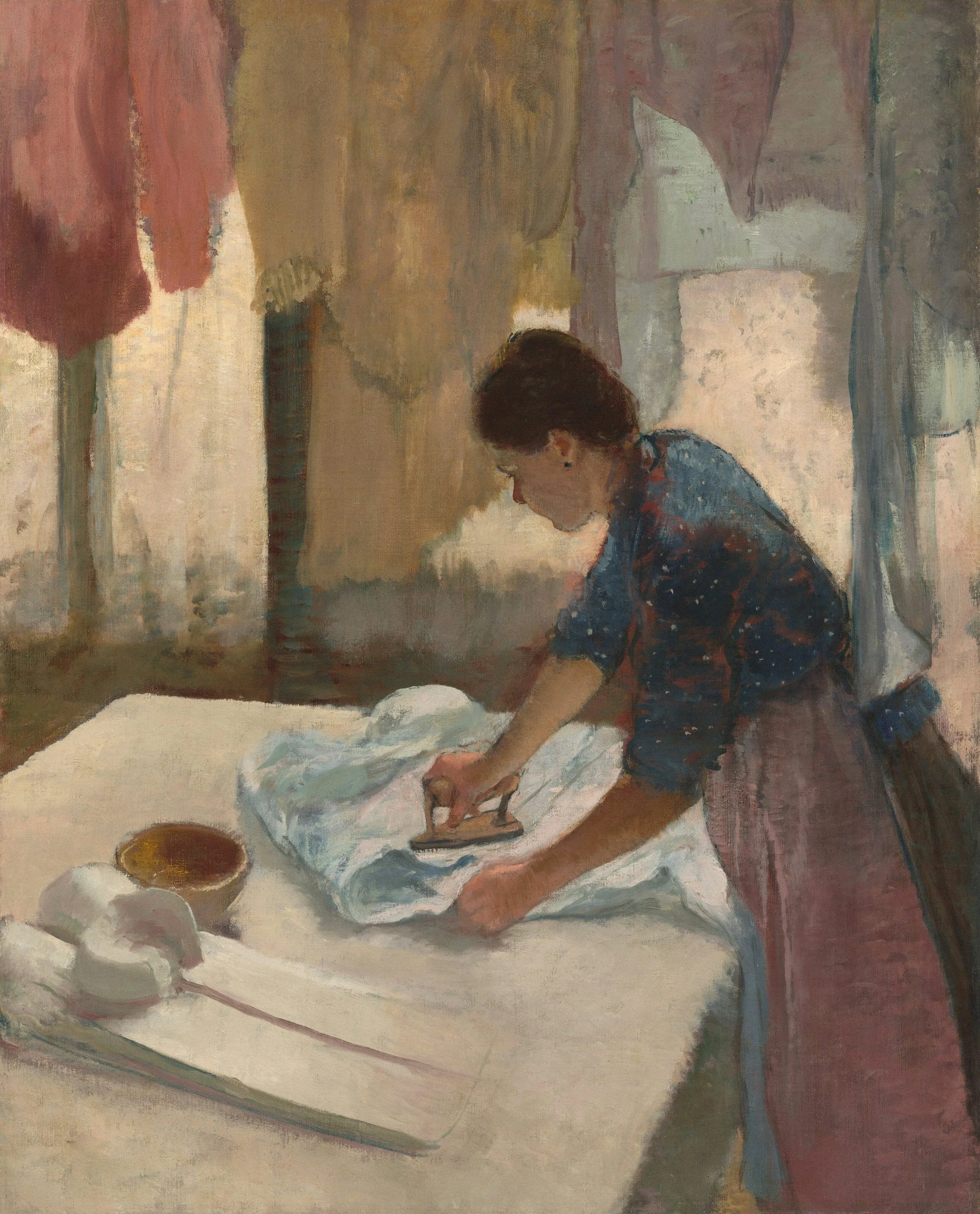 A woman with dark hair tied back, wearing a blue top, is kneeling and ironing a piece of white fabric on a table. There are white dishes, possibly with food or ingredients, nearby. The background has an impressionistic style with soft, muted colors and abstract shapes.