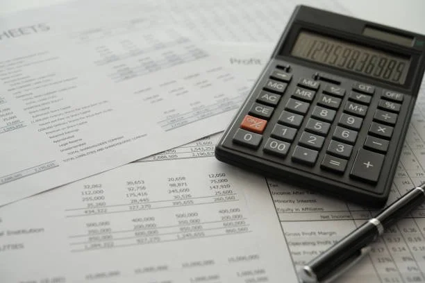 Calculator, pen, and financial documents on a desk.