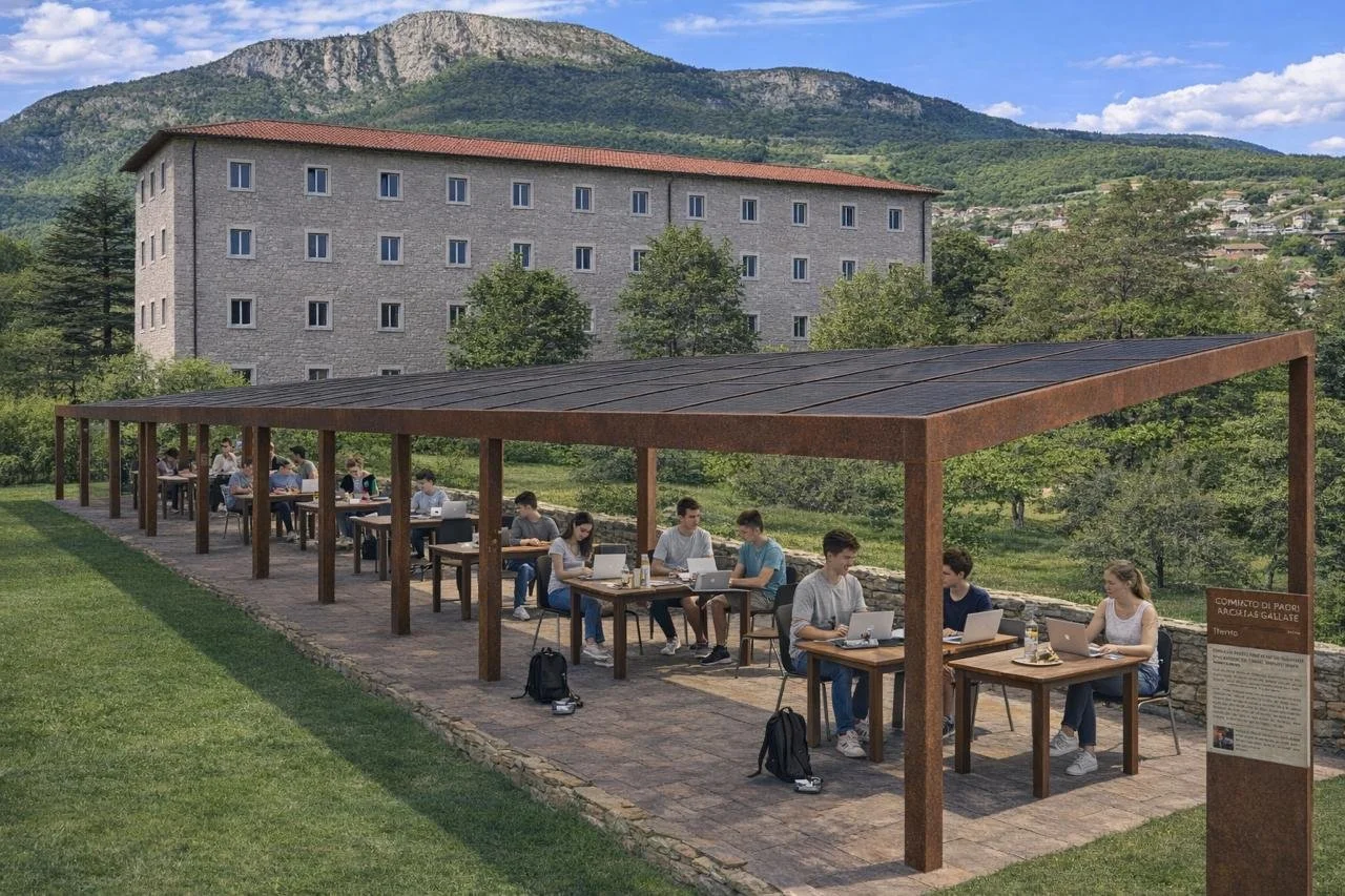 Group of students studying outdoors under a large covered structure, with a historic-looking building and green mountains in the background.