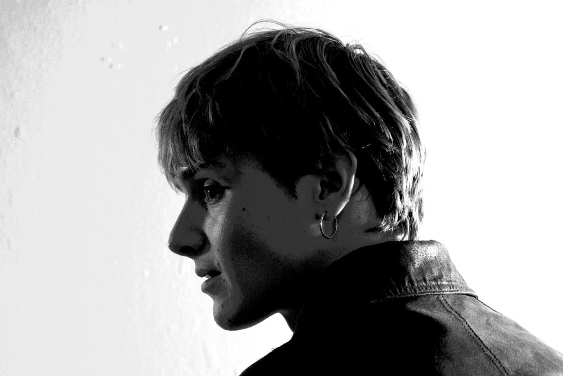 Black and white side profile of woman with short hair, hoop earring, and leather jacket.