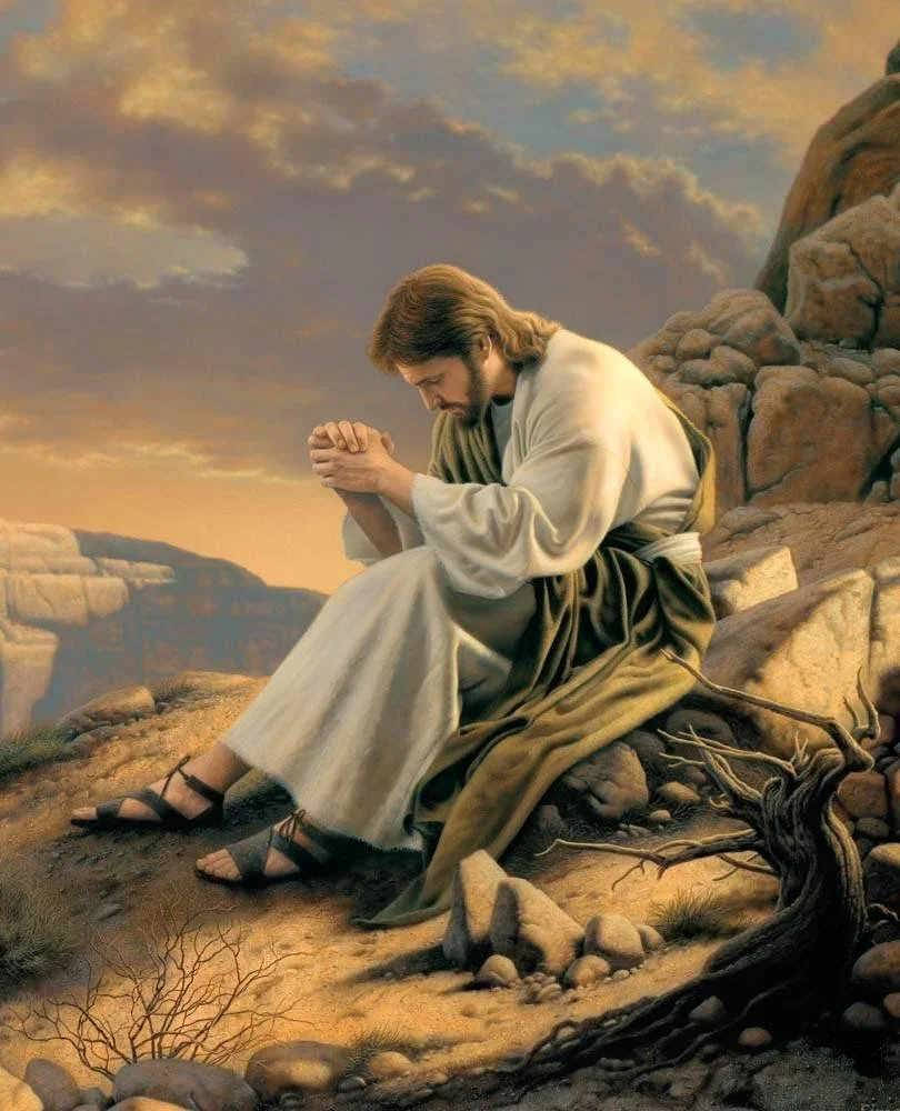 Jesus Christ praying on a rocky hillside during sunset with a cloudy sky in the background.