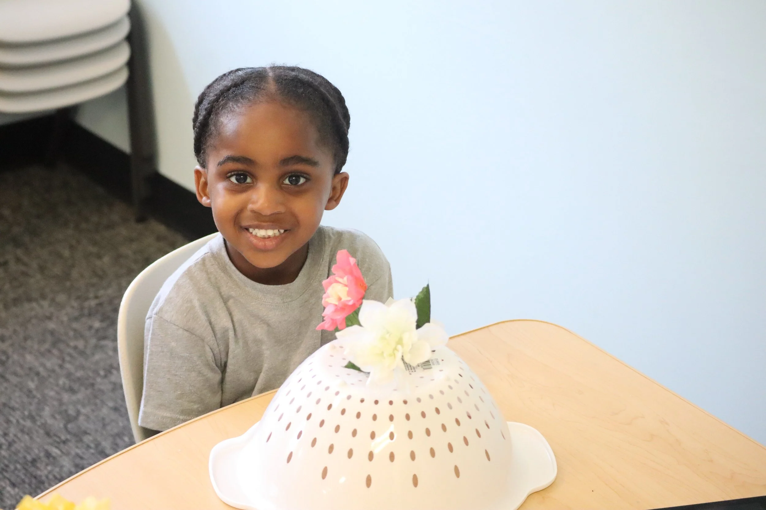 Young girl smiling at a birthday celebration with a polka-dotted cake with flowers on top.