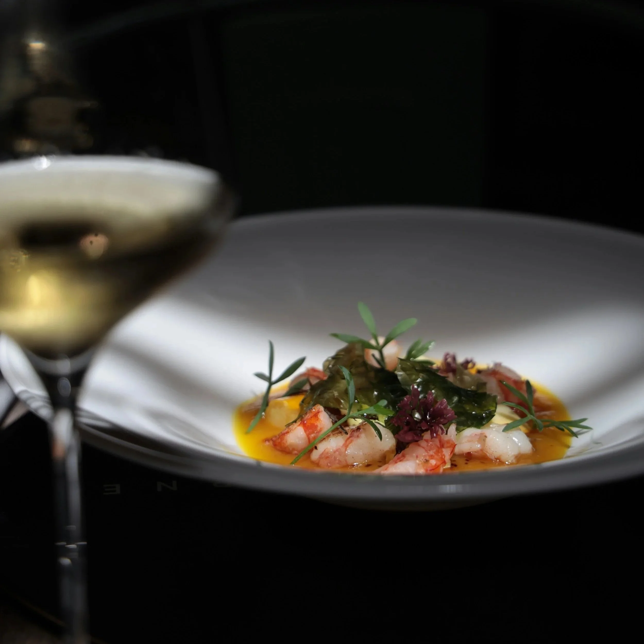 Fine dining dish with wine served in dim restaurant light