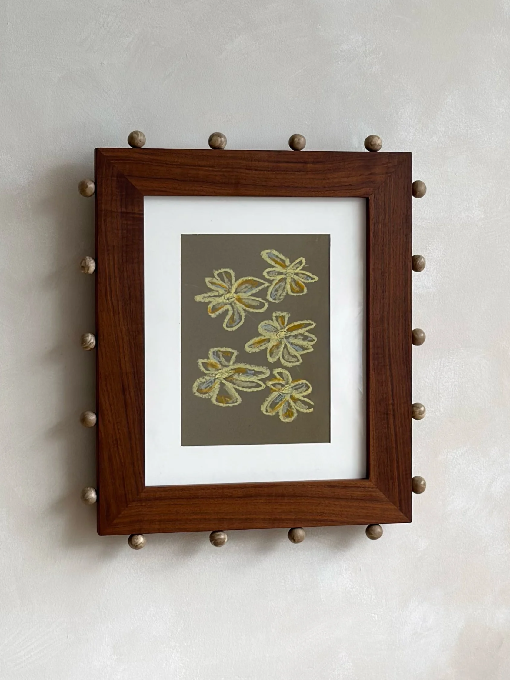 Wooden framed mirror decorated with ceramic ball accents around the frame, hanging on a plain white wall.