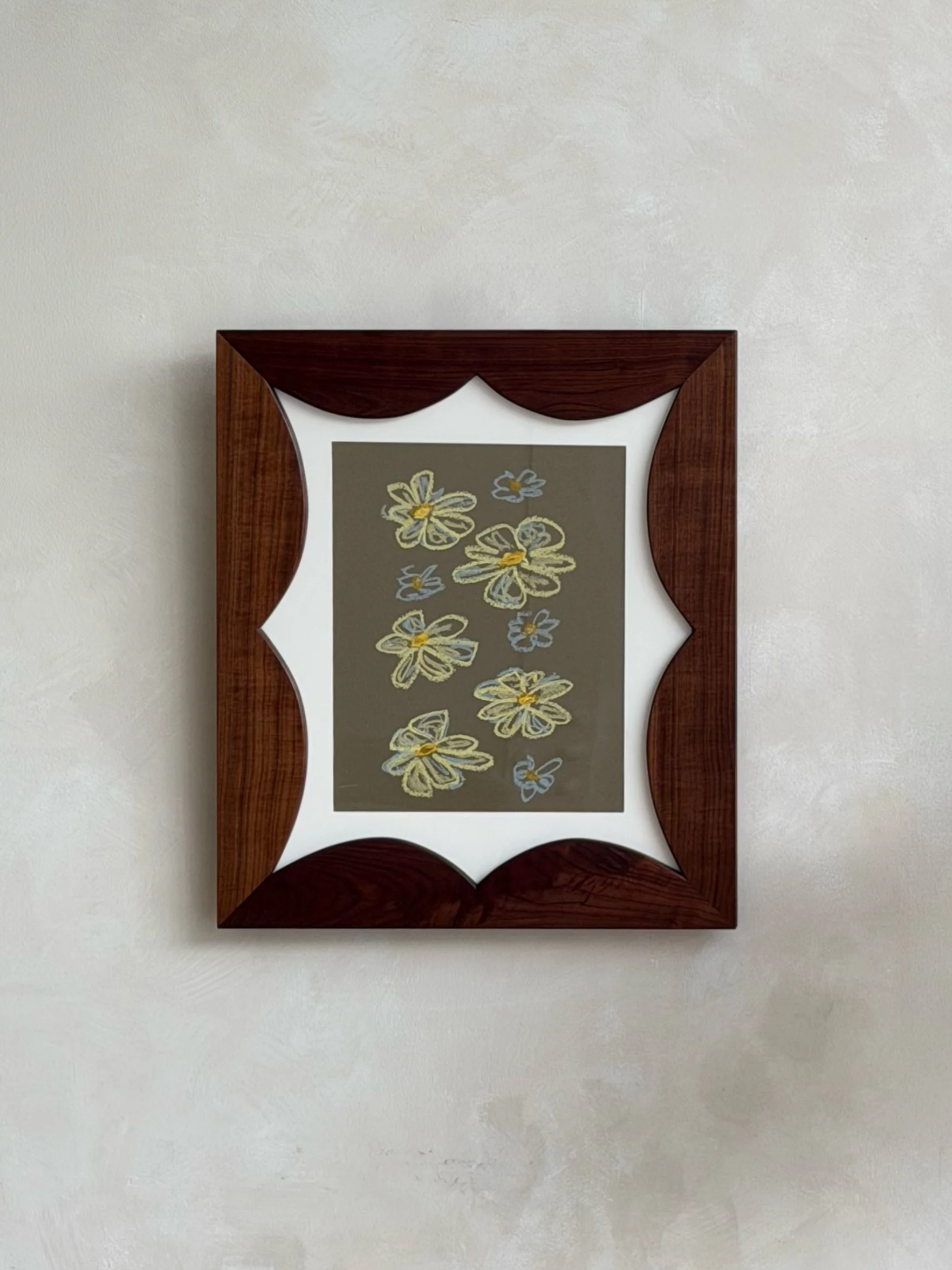Decorative mirror with a wooden frame hanging on a white wall. The mirror has a floral design inside with yellow, blue, and white flowers.
