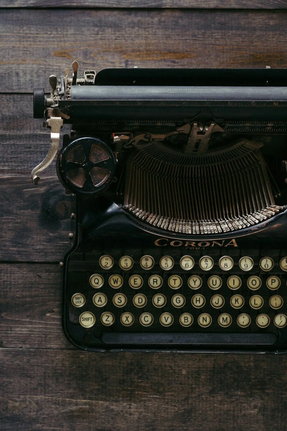 Vintage black typewriter with cream-colored keys on wooden surface