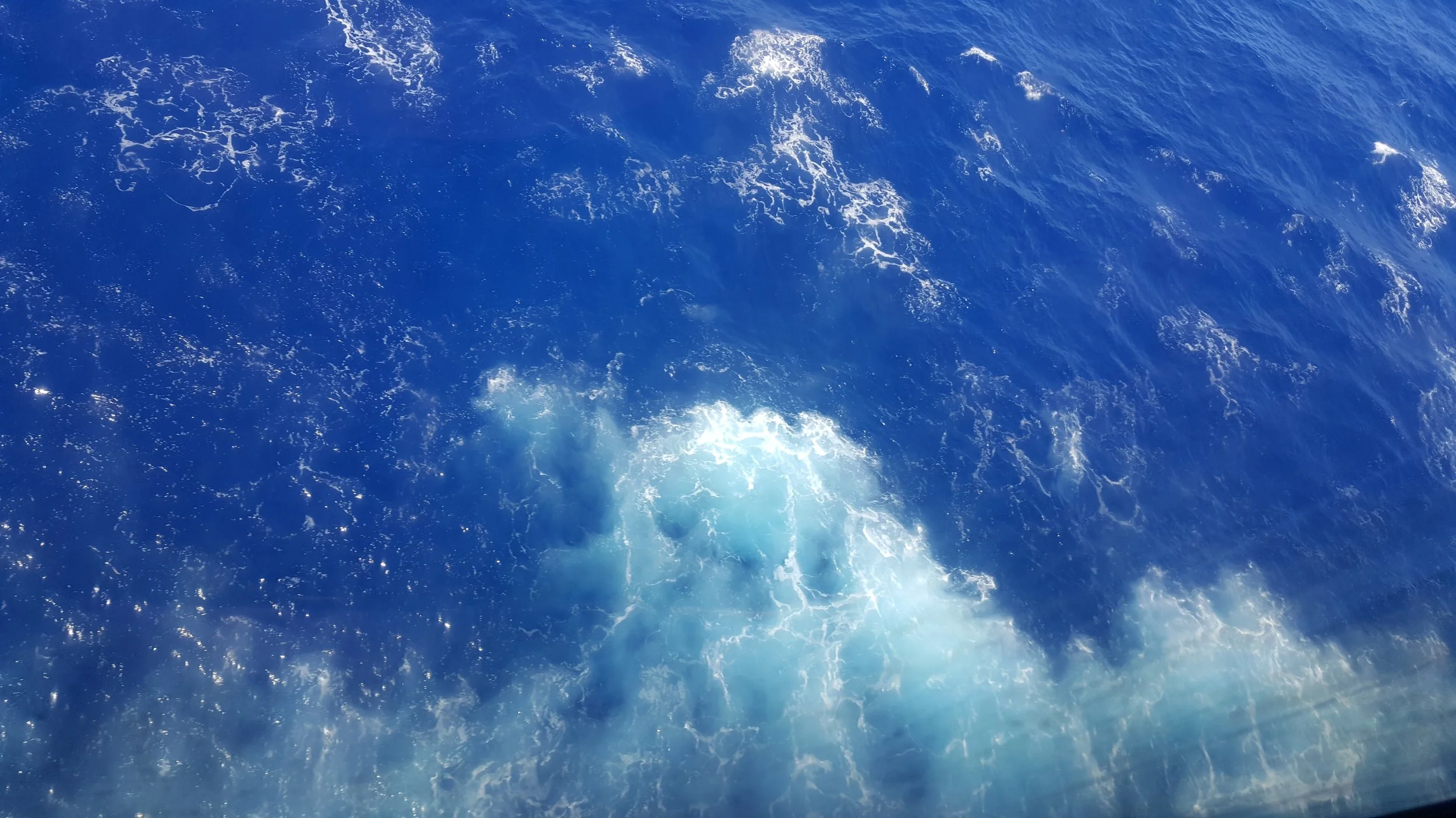 A photo of the ocean with white foam and waves.