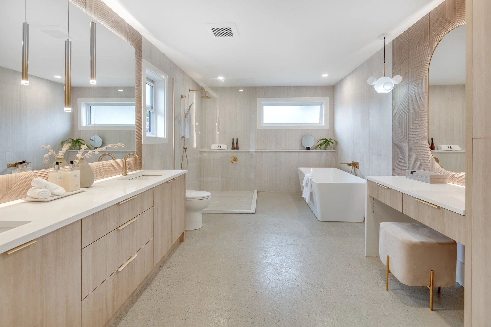 Modern bathroom with beige cabinetry, a large mirror, a bathtub, a walk-in shower, and decorative accents like plants and vases.