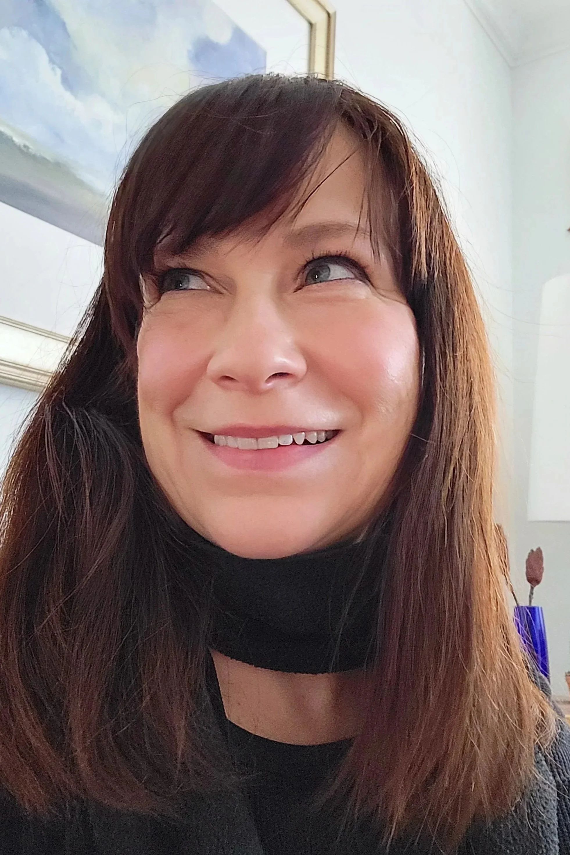 The Owner of Clarke Atelier smiling with her cousin's painting in the background professional digital photo organizer in Toronto Ontario Canada.