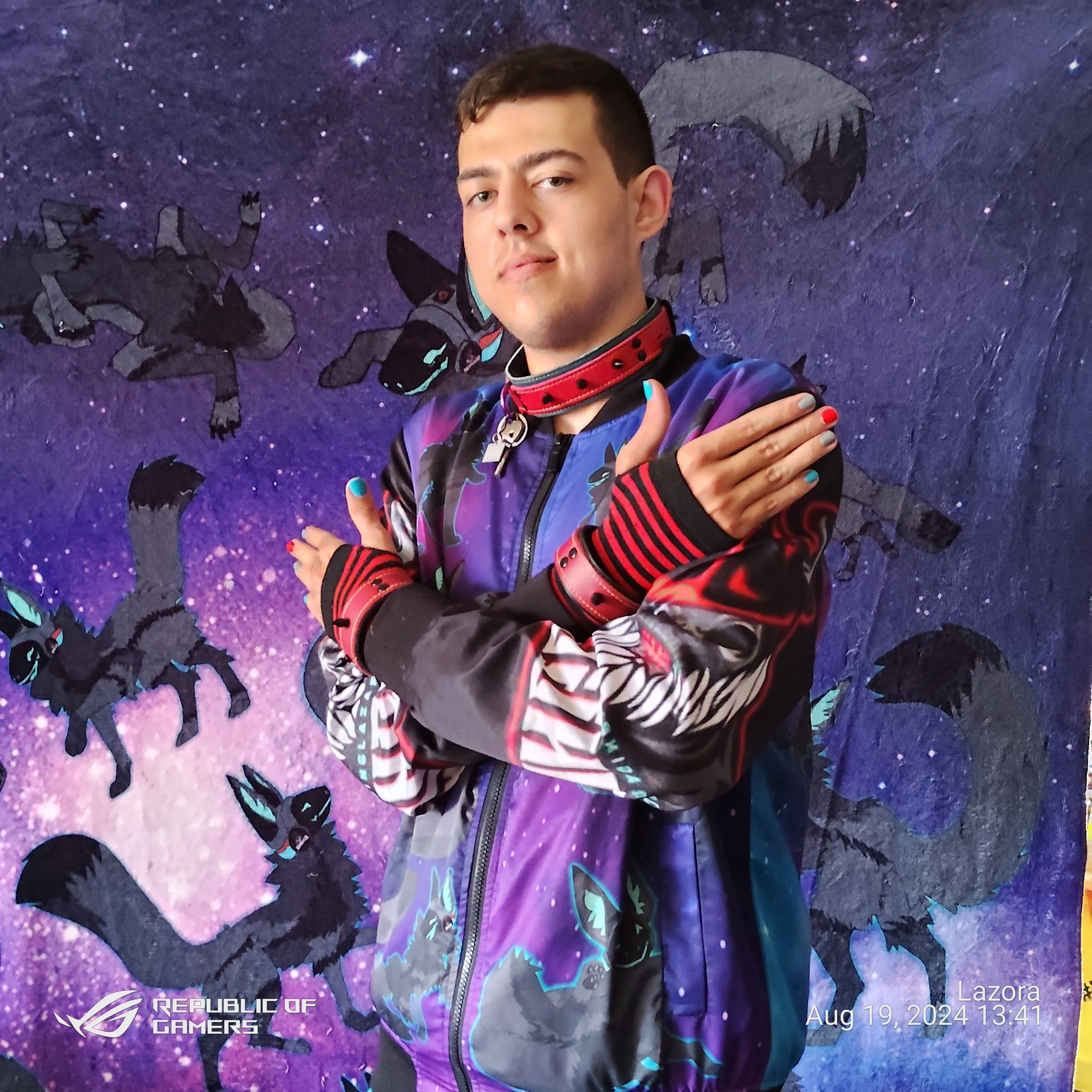 A young man with short dark hair and light skin posing with arms crossed against a cosmic-themed background featuring large black dragon silhouettes and purple galaxy colors. The bottom left corner displays the logos of Republic of Gamers and ASUS, w