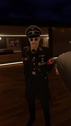 Person dressed in Nazi uniform with swastika armband, black uniform, and sunglasses