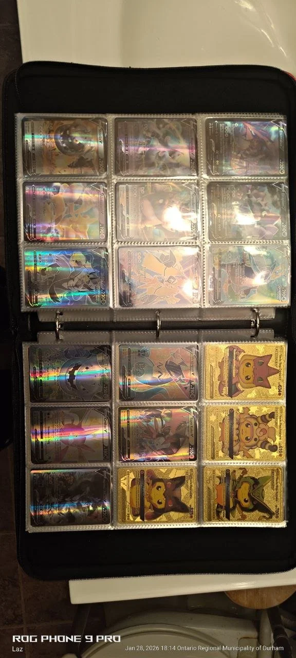 Photo of a Pokémon card binder open on a table, showing a collection of various holographic and illustrated Pokémon cards, including Pikachu and other characters, organized in clear sleeves.