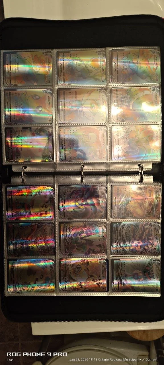 A collection of Pokémon cards stored in a binder with transparent sleeves. The cards are shiny and holographic, showing various Pokémon characters.