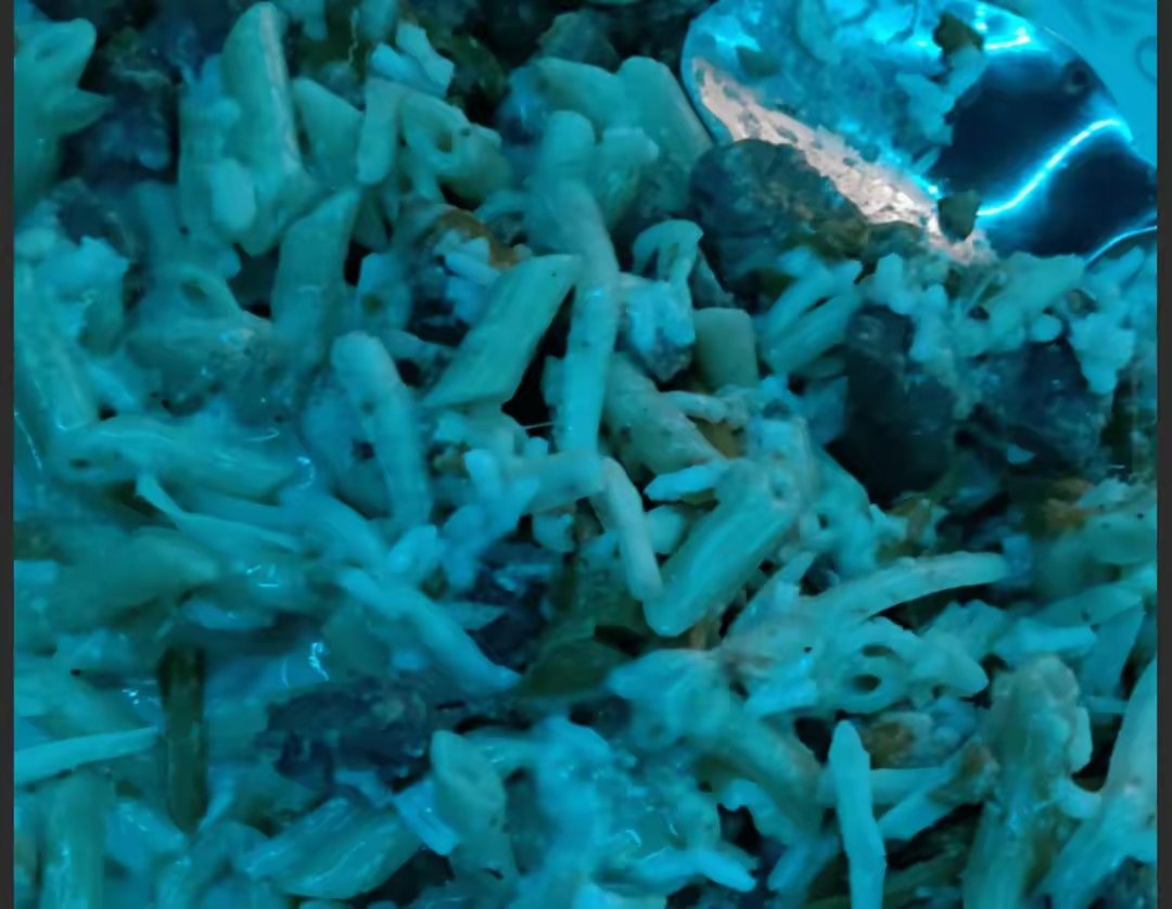 A close-up image of a pile of cooked crab legs and shells with a bluish lighting.