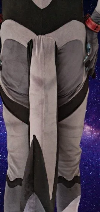 A person wearing a gray and black Stormtrooper costume from the Star Wars franchise, with a galaxy background.