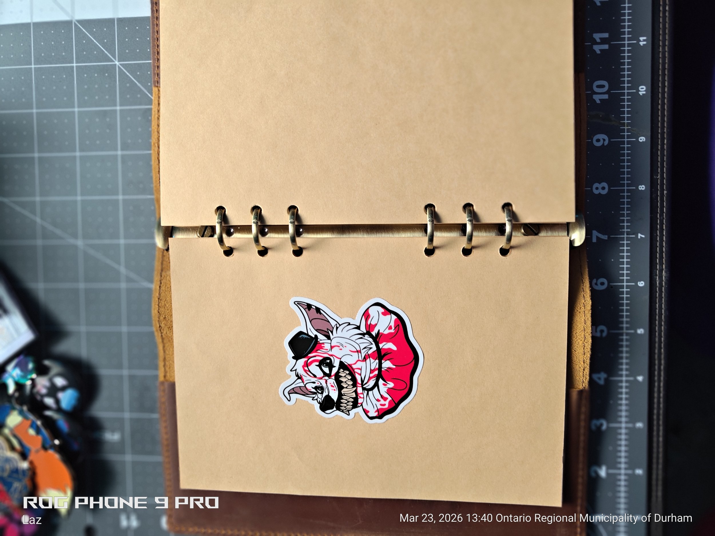 A sticker of a fierce, snarling animal, possibly a wolf, with a stylized appearance, sticks to a beige paper or cardboard surface.