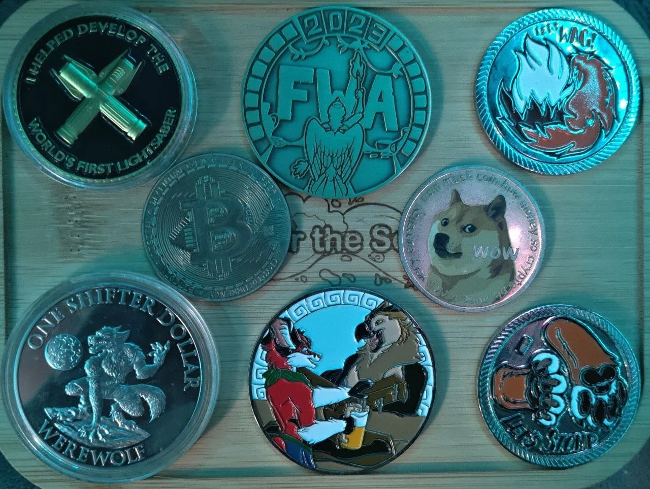 A collection of nine coins with various designs on a light wooden surface.