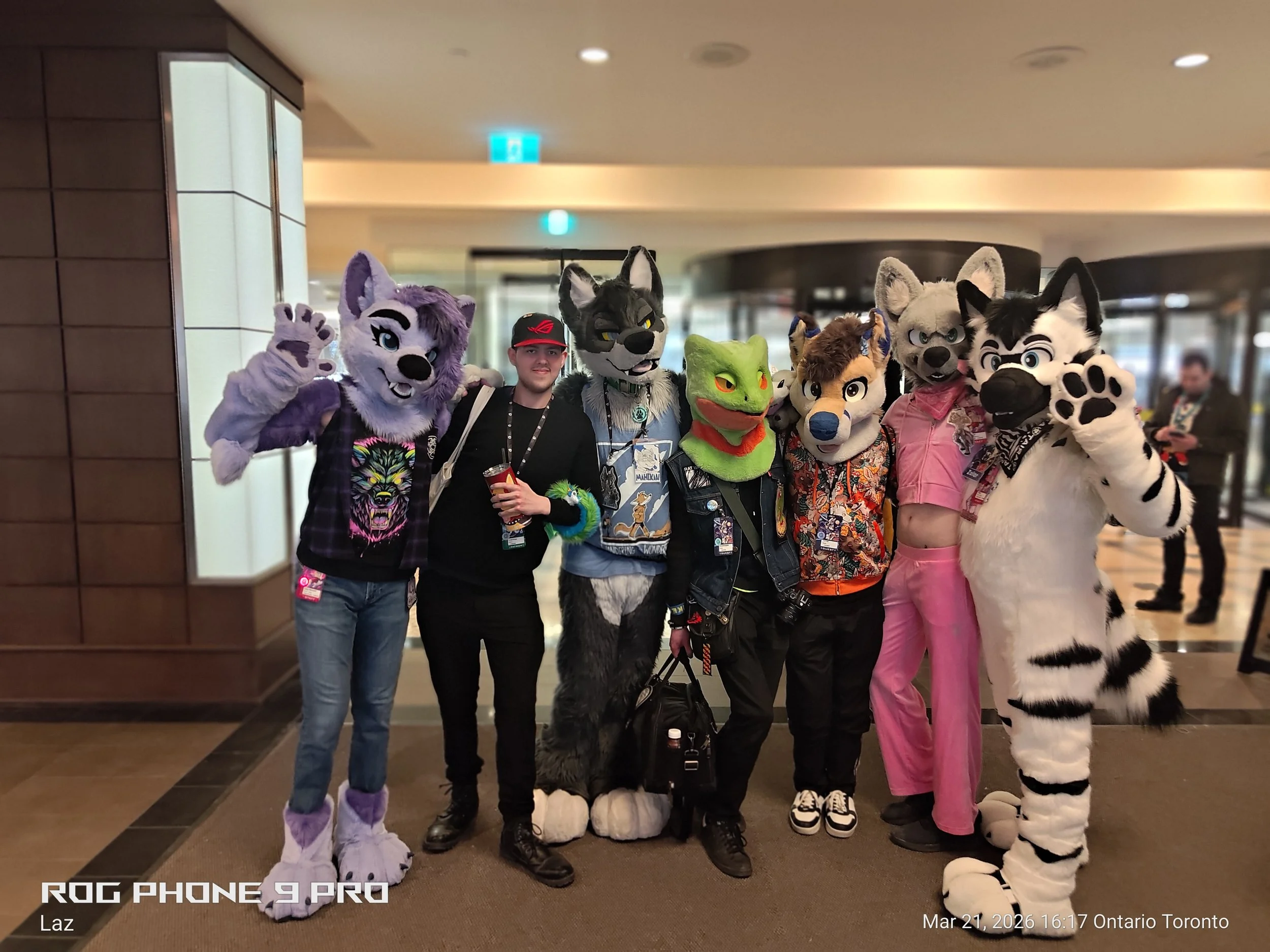 Group of people in furry animal costumes posing together indoors at a convention.