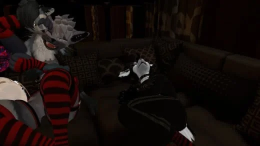 Group of fursuit costumed characters sitting on a couch in a dimly lit room.