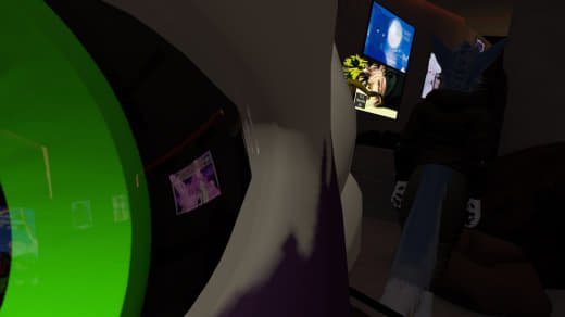 Person sitting at a desk with multiple monitors, one showing a moon graphic, in a dimly lit room.