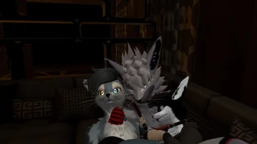 Two anthropomorphic characters, a cat with blue eyes and a wolf, sitting on a couch in a room with bookshelves and framed pictures, engaged in a close interaction.