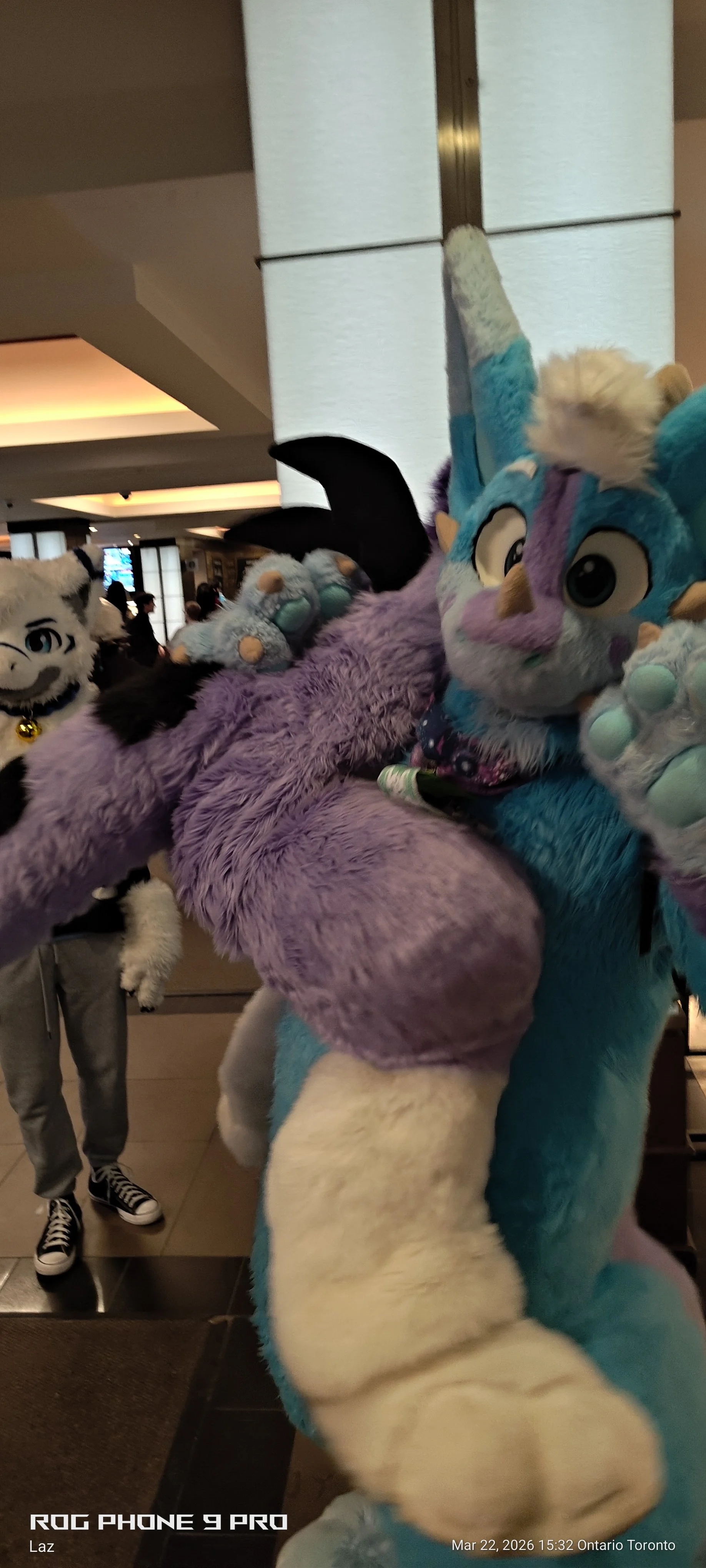 Several people dressed in colorful, furry animal costumes, known as furries, at a public indoor event.