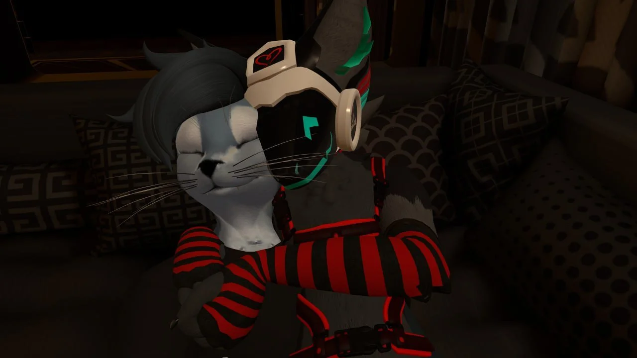 A digital character, dressed as a cat with a human face, wears headphones and a vest, sitting with their arms crossed on a sofa with patterned pillows in a dimly lit room.