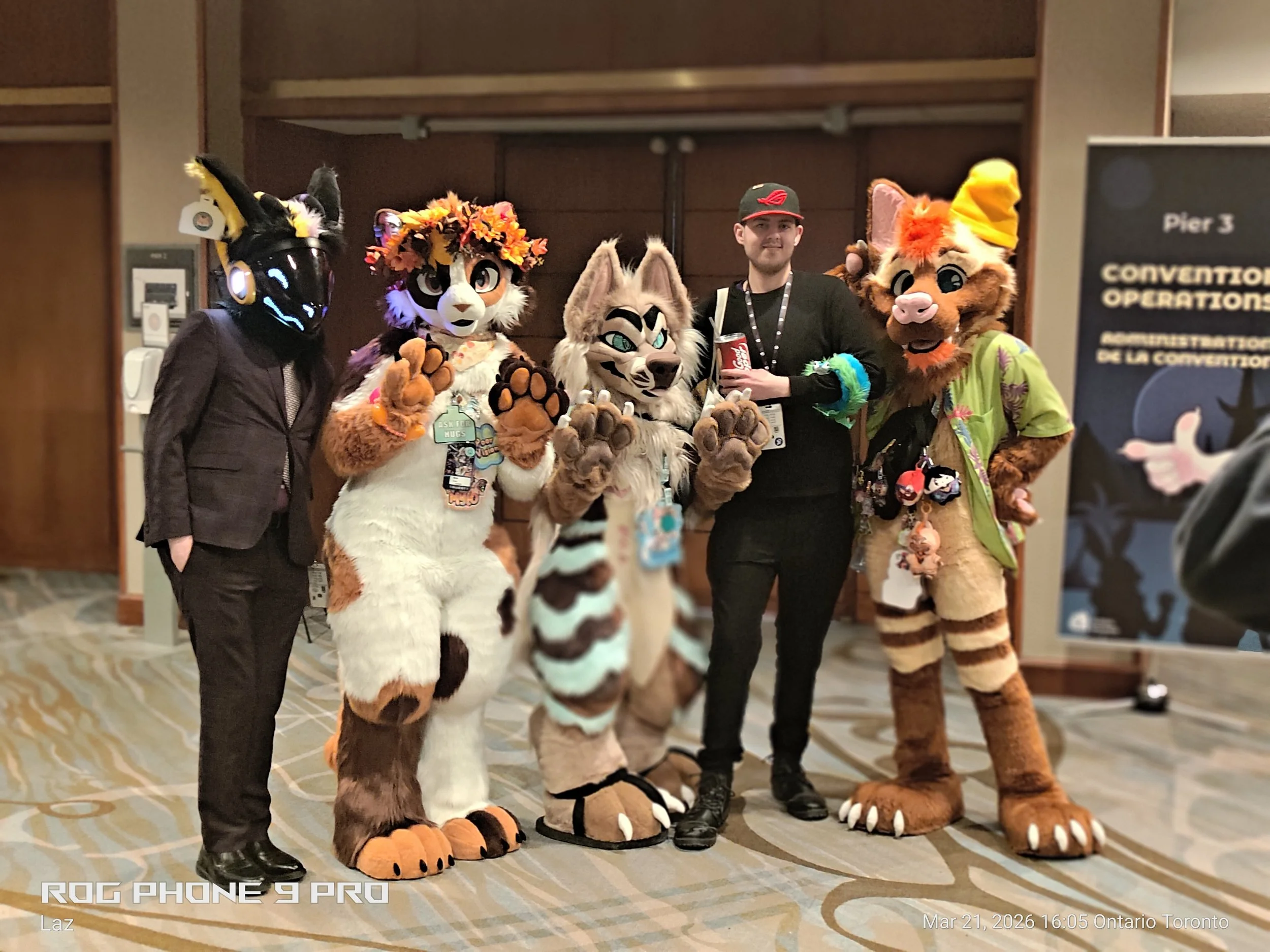 Five people dressed in colorful animal costumes, including a wolf, fox, and lion, posing indoors at a convention event.