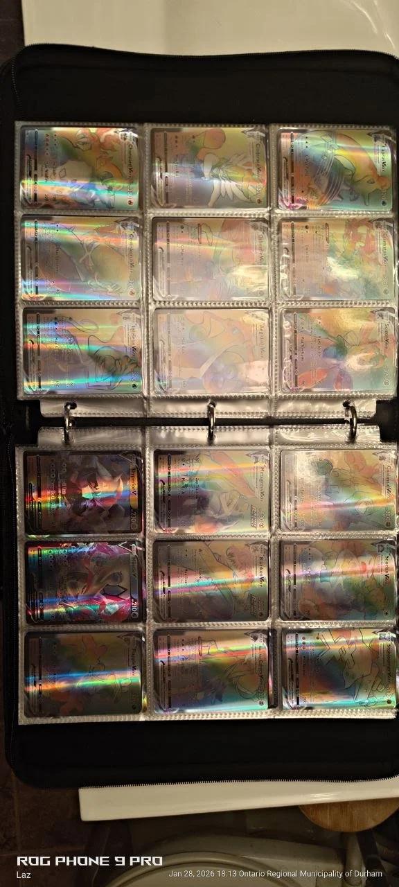 A collection of Pokémon cards stored in clear plastic sleeves inside a black binder. The cards have holographic designs.