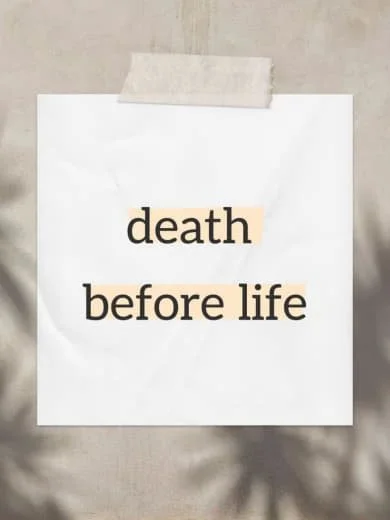 A handwritten note with the words "death before life" written on a piece of paper taped to a wall.