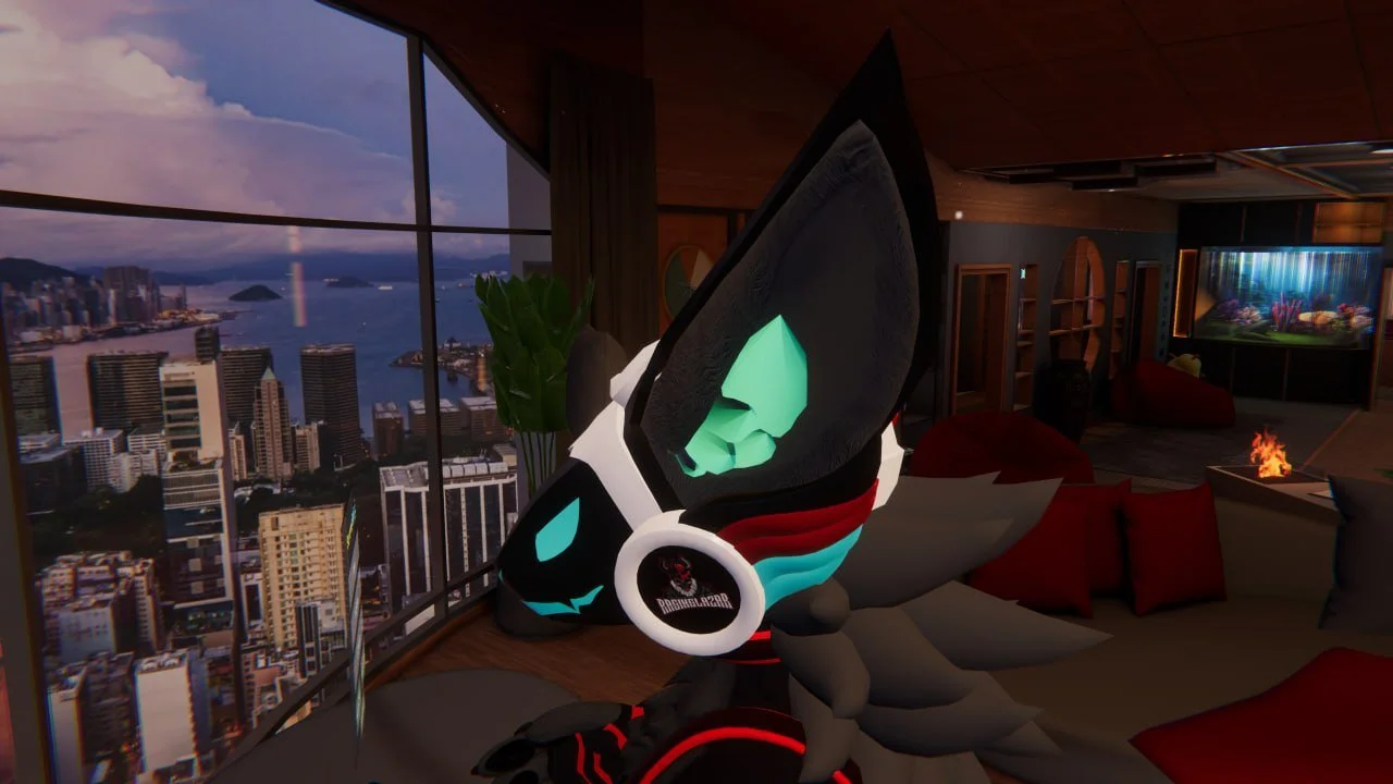 A stylized digital creature with glowing green face, wearing a white headset with a black logo, sitting on a couch inside a modern apartment with floor-to-ceiling windows showing a city skyline and water view.