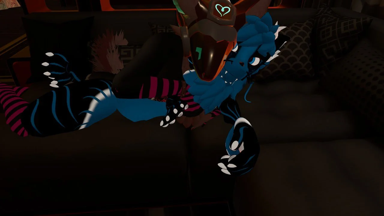 Animated blue and black anthropomorphic tiger character lying on a dark couch, holding a large mechanical object with glowing teal lines, surrounded by patterned pillows.