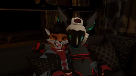 A person wearing a cat costume and a robotic helmet taking a selfie in a cozy room with pillows and a patterned blanket.