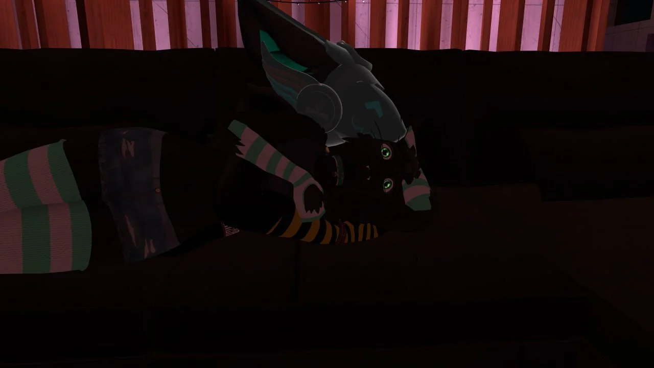A person with a robot head lying on a dark couch in a dimly lit room with wooden paneling.