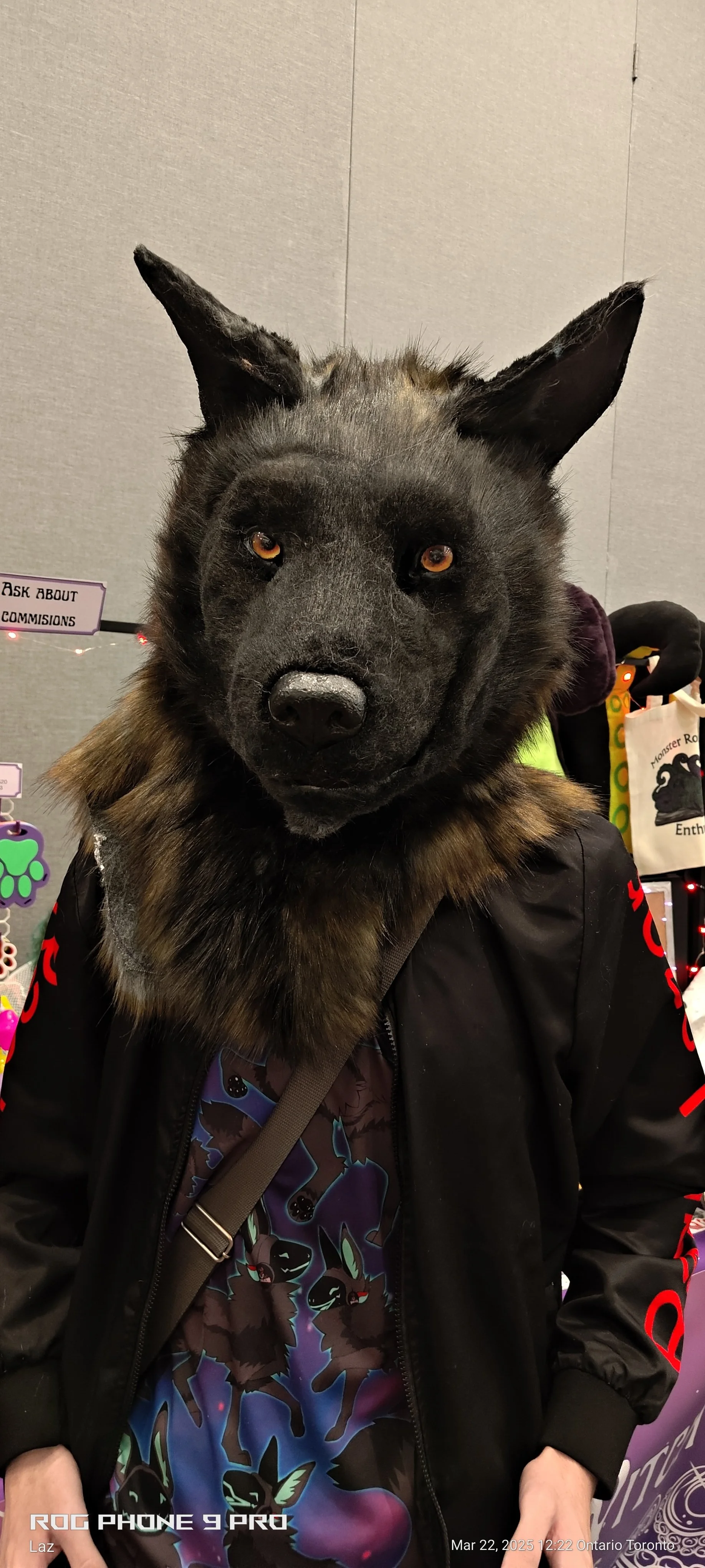 A person wearing a wolf mask with realistic features, including pointed ears and amber eyes, in a room with various colorful merchandise and signs.