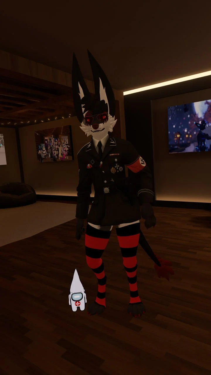 An anthropomorphic wolf character in a dark uniform with badges, armbands, and sunglasses standing in a modern room with a large screen and framed photos, with a small cartoon astronaut figure on the floor.
