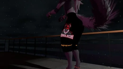 Person standing on a balcony at night, wearing a black skirt with a red demon face design and text, and a pink top with long hair.