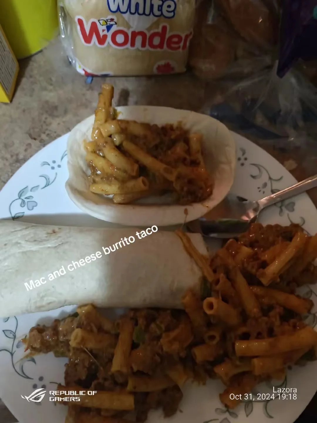 A plate with macaroni and cheese burrito, a small bowl of macaroni and cheese with meat sauce, and some leftover pasta with meat sauce on a table with a pack of Wonder bread in the background.