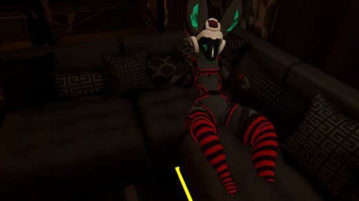 A person wearing a cartoonish animal mask and red-and-black striped leggings, sitting on a dark couch surrounded by patterned pillows.
