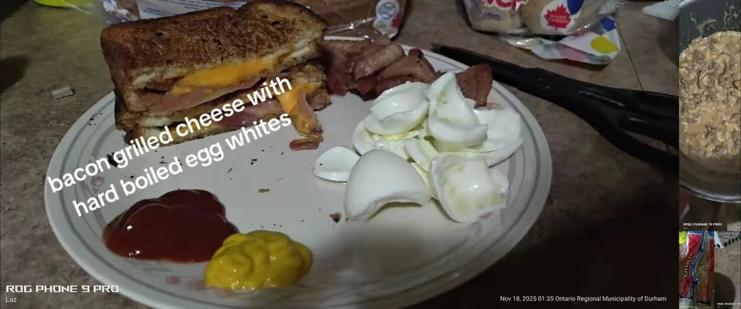 Plate with bacon grilled cheese sandwich, hard boiled egg whites, sliced boiled eggs, and condiments including ketchup and mustard.