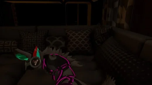 A small dog wearing a pink harness and a colorful LED cheeky headband, lying on a couch with patterned pillows in a dimly lit room.