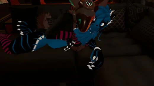 Person in a blue and black dragon costume sitting on a dark couch.