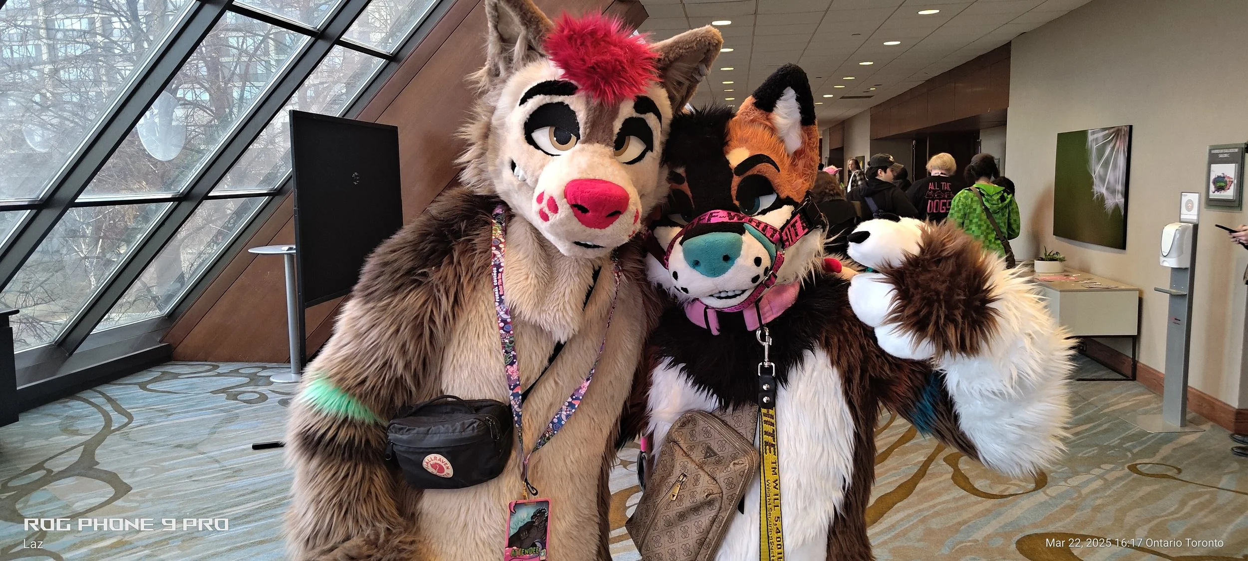 Three individuals dressed in colorful animal costumes, including a lion, a tiger, and a wolf, pose together indoors at a convention or event.